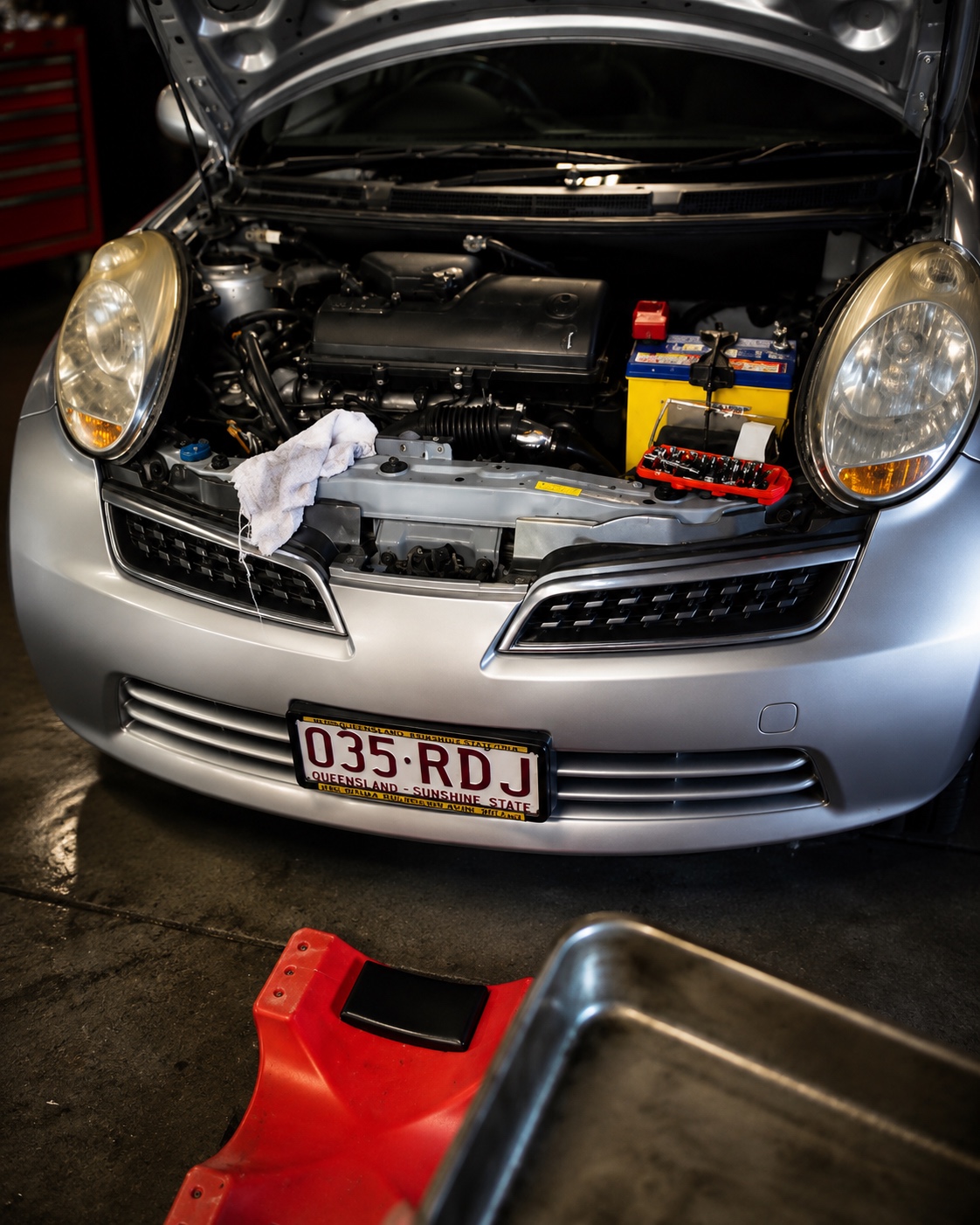 Red vehicle with open bonnet and air filter box in front