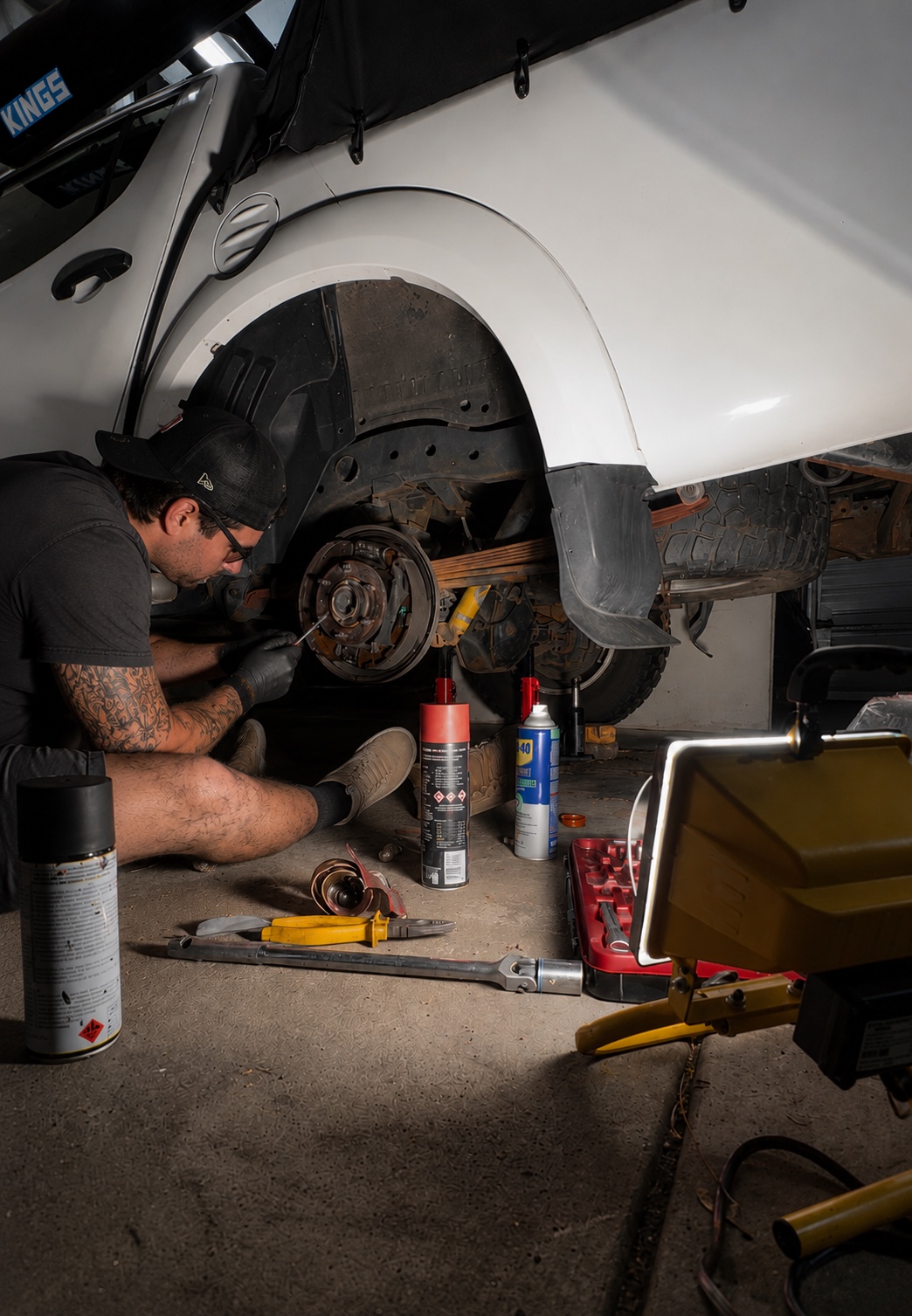 Mechanic servicing brake area on elevated vehicle